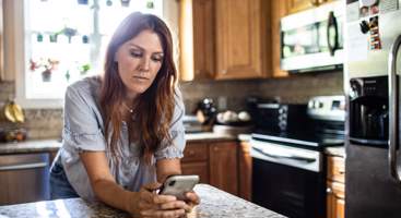 Woman using smartphone phone in kitchen